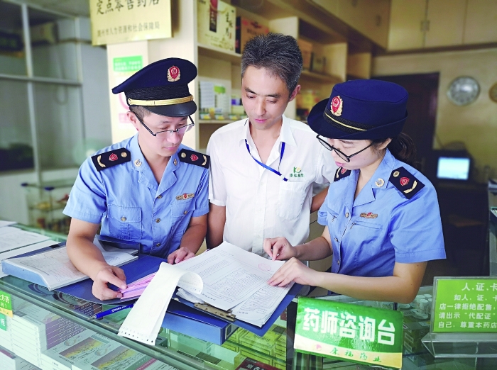 執(zhí)法人員在一家藥店檢查特殊藥品進(jìn)貨臺(tái)賬。