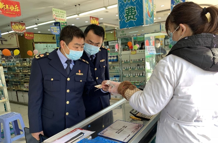 執(zhí)法人員在一家藥店檢查口罩質(zhì)量和進(jìn)銷(xiāo)價(jià)單據(jù)