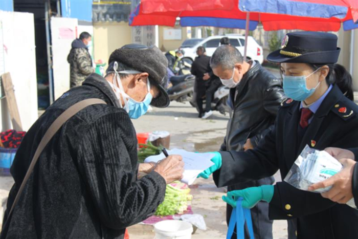 圖為鷹潭市市場監(jiān)管局工作人員向經(jīng)營戶發(fā)放口罩。