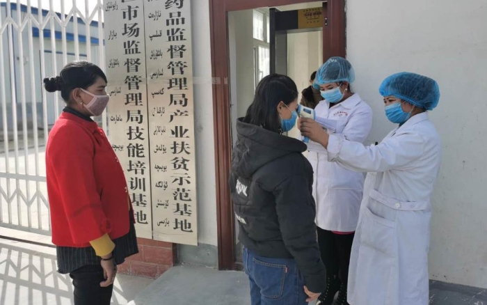 工人在進(jìn)入工廠前測(cè)量體溫并登記。（駐村工作隊(duì)供圖）