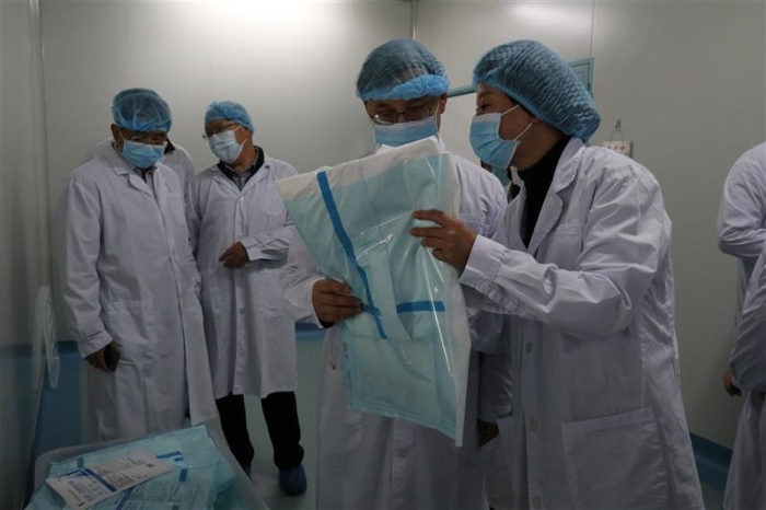 圖為云南省藥監(jiān)局黨組書記、局長劉本軍（右二）檢查該企業(yè)生產(chǎn)的醫(yī)用一次性防護(hù)服。（云南省藥監(jiān)局供圖）