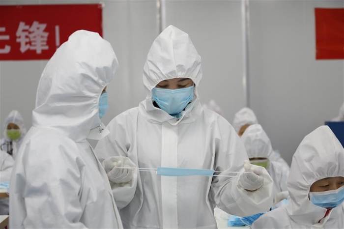 新疆維吾爾自治區(qū)藥監(jiān)局駐企特派員馬小華（右）正在與企業(yè)質(zhì)量負(fù)責(zé)人溝通口罩生產(chǎn)中遇到的問(wèn)題。（馬少賓 攝）