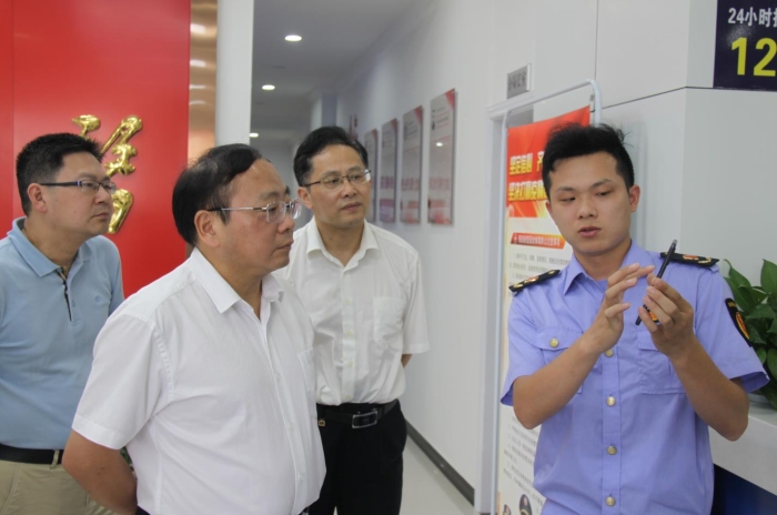 上官新晨（左二）在鷹潭市局東湖分局觀看基層執(zhí)法人員演示如何運用智慧市場監(jiān)管網(wǎng)格化管理平臺開展監(jiān)督檢查工作等情況。