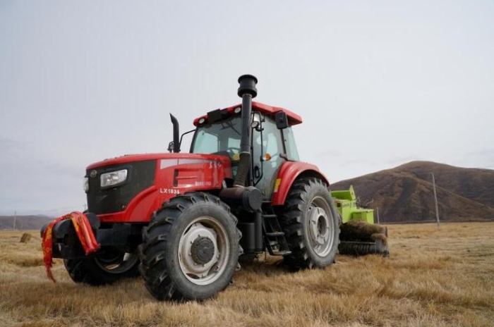 在青海省果洛藏族自治州甘德縣江千鄉(xiāng)，一位牧民正在飼草基地駕駛打捆機工作。（2020年11月3日攝）。新華社記者陳凱 攝