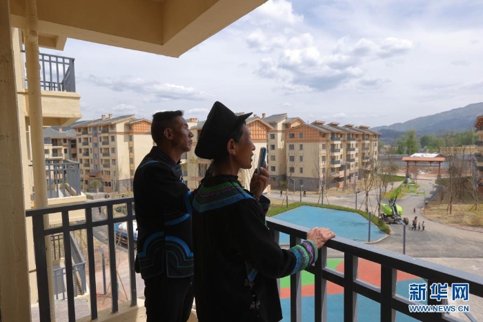 在四川省昭覺縣城易地扶貧搬遷安置點(diǎn)南坪社區(qū)，剛搬遷到新家的“懸崖村”村民莫色達(dá)體夫婦在陽臺(tái)給親戚打電話（2020年5月13日攝）。新華社記者 江宏景 攝