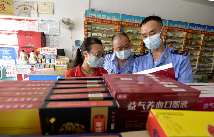圖為執(zhí)法人員在一家藥店檢查中成藥質(zhì)量。