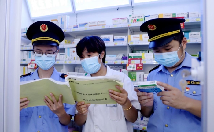 執(zhí)法人員查看藥店網絡藥品銷售登記并核對處方藥處方單