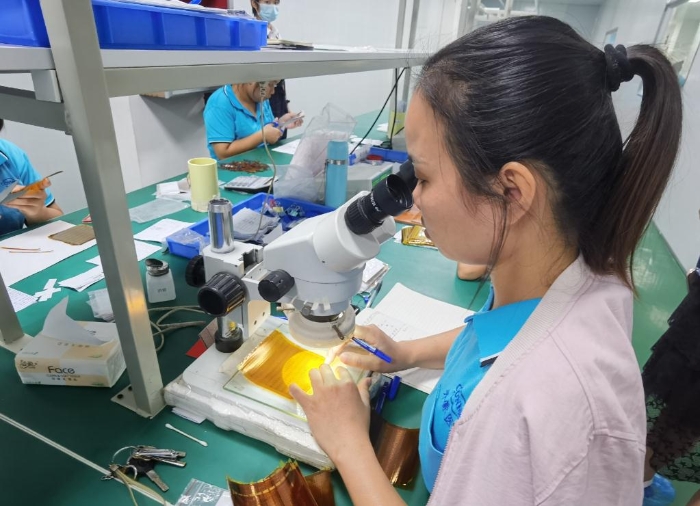 開蒙醫(yī)療員工在用顯微鏡檢查人體成分分析儀芯片上的箔片集成電路是否有缺陷。