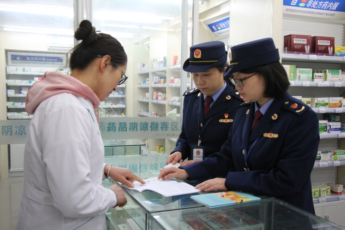 圖為執(zhí)法人員在佰藥之家大藥房發(fā)放安全用藥科普手冊。