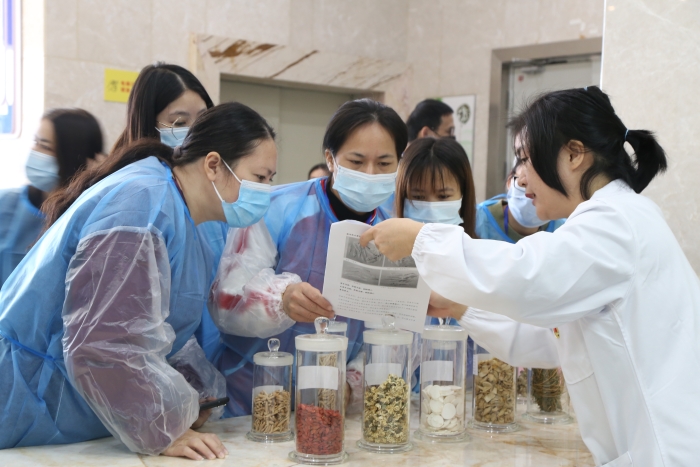 圖為工作人員為市民代表講解中藥材真?zhèn)舞b別知識。