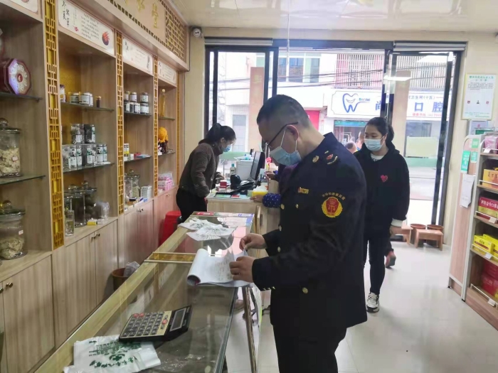 圖為執(zhí)法人員在一家藥店查看登記臺賬。