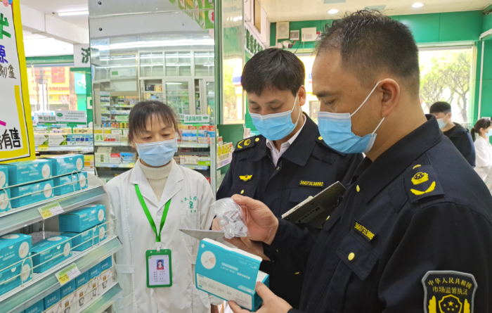 圖為執(zhí)法人員在一藥店查看抗原檢測試劑材料。
