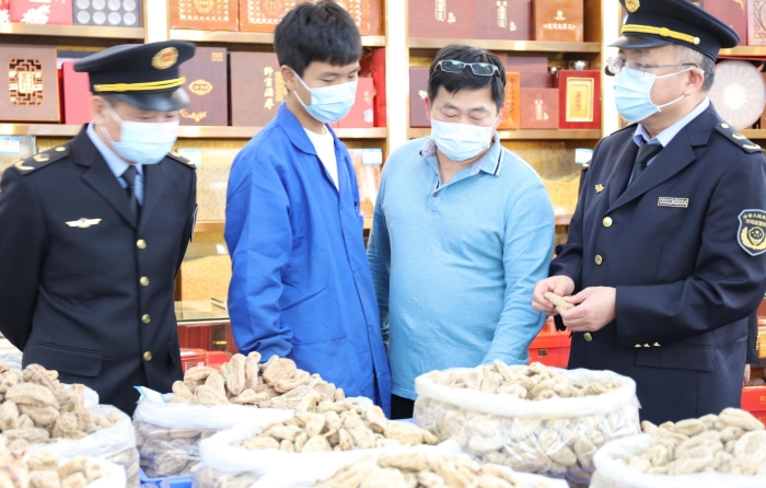 秦繼紅（右一）在中藥材市場(chǎng)門(mén)店查看。（喻燦華 攝）