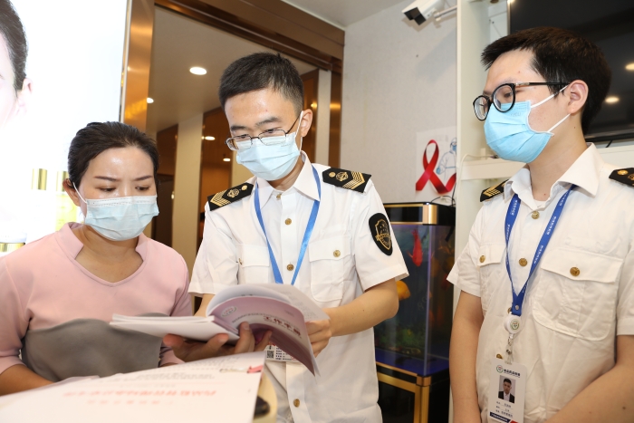 圖為抽檢人員向經(jīng)營者宣貫化妝品監(jiān)管法規(guī)文件。