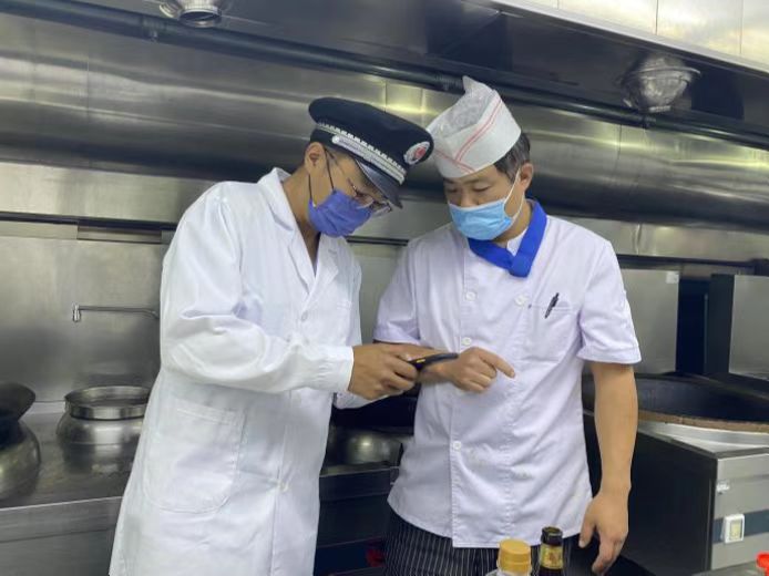 圖為海淀區(qū)市場監(jiān)管局執(zhí)法人員檢查學(xué)校食堂食品安全。