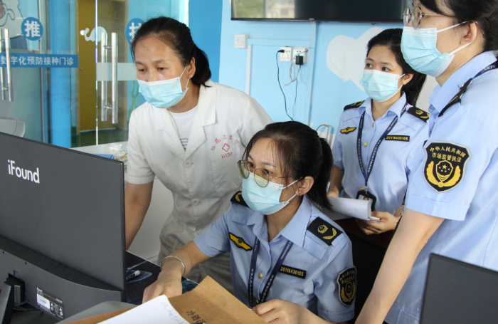 圖為鐘山縣市場監(jiān)管局執(zhí)法人員在一家疫苗接種單位檢查相關資質文件。