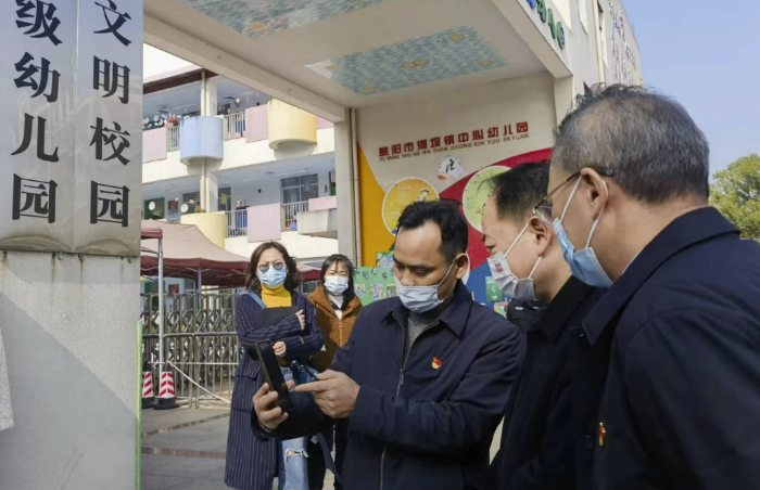 圖為樂(lè)運(yùn)成（右二）通過(guò)手機(jī)客戶(hù)端查看大通湖區(qū)第一實(shí)驗(yàn)幼兒園廚房實(shí)時(shí)視頻。