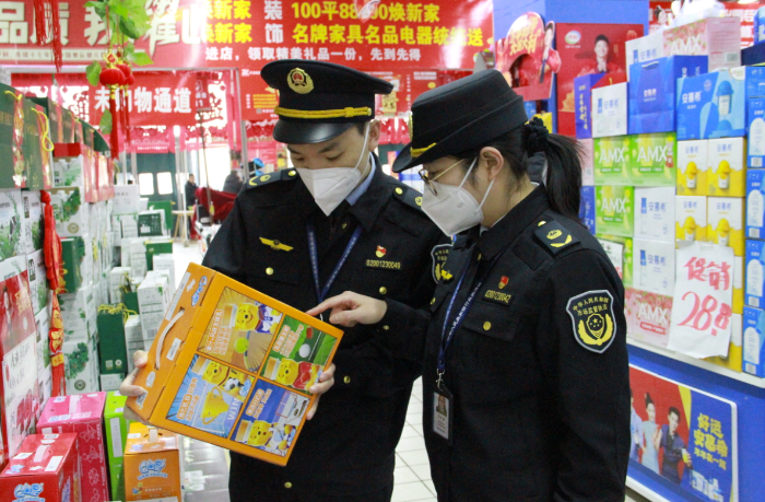 圖為該局執(zhí)法人員在一家商場檢查在售食品是否超過保質期。