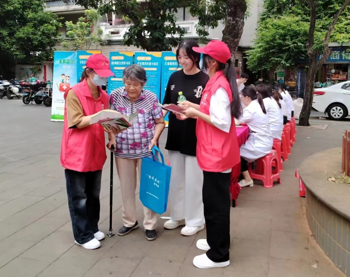 圖為工作人員向過往居民發(fā)放“全民監(jiān)測”科普宣傳資料。