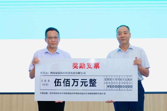 圖為研討會現(xiàn)場，陜西省藥監(jiān)局二級巡視員王志宏向西安康拓醫(yī)療技術股份有限公司董事長胡立人頒發(fā)500萬元醫(yī)療器械創(chuàng)新獎勵資金。